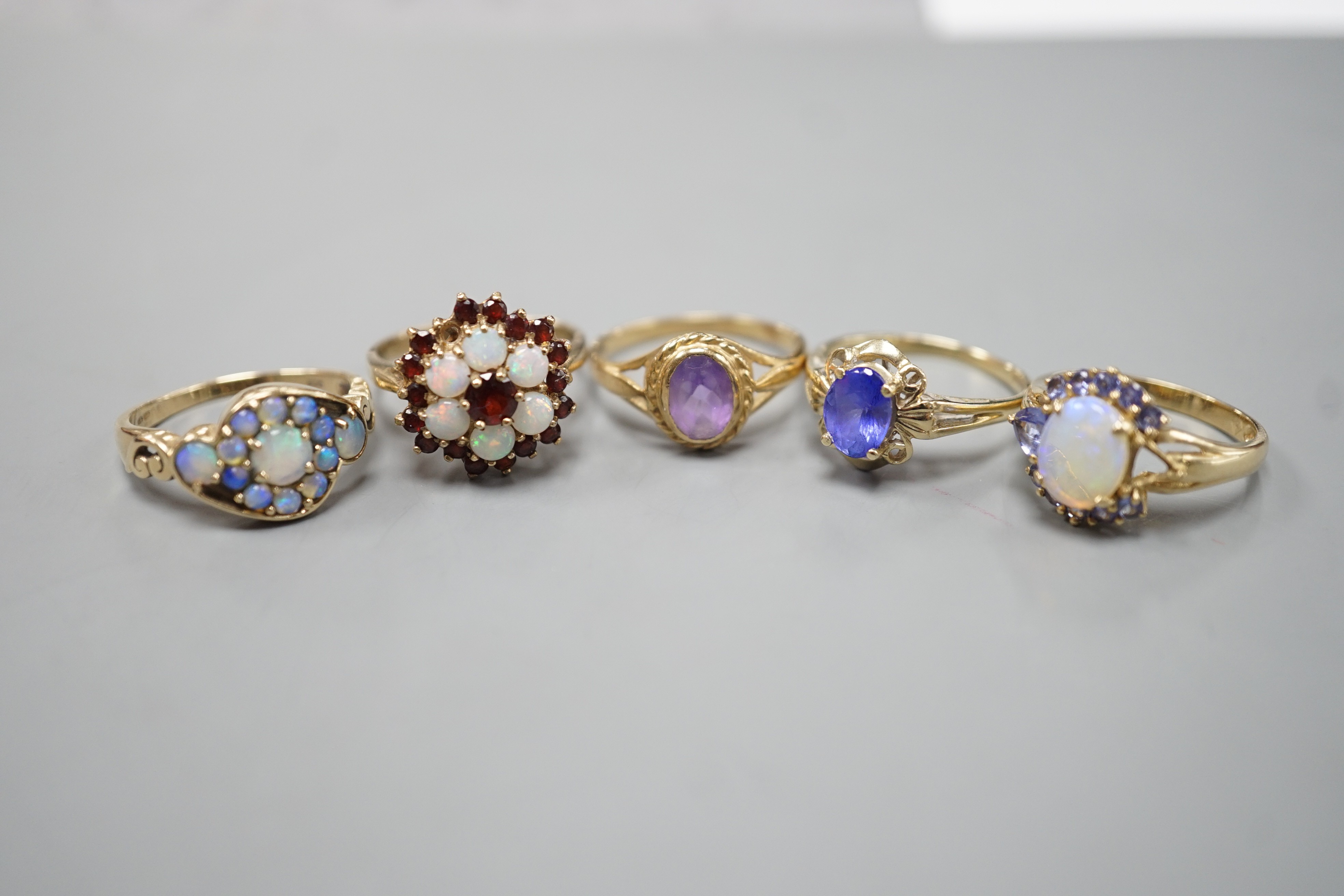 Five assorted modern 9ct gold and gem set dress rings, including, white opal cluster, garnet and white opal cluster and amethyst